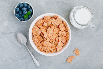Whole grain breakfast cereal flakes with fresh blueberries and milk. Top view, copy space