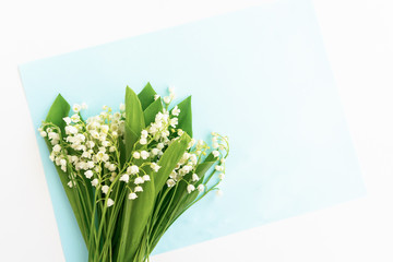 Tender spring lilies of the valley on a blue background, top view. Background with lily of the valley flowers. Copy space. place for text and a bouquet of lilies of the valley.