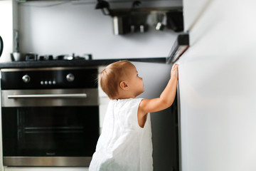 girl child toddler opens kitchen cabinets at home