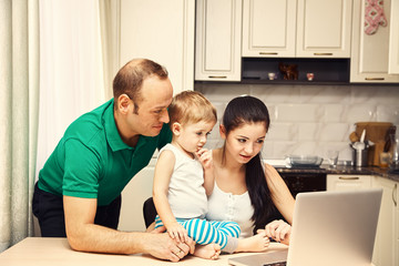 young family with a child does online shopping using a credit card in the laptop at home.