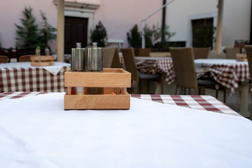 The interior of the restaurant on the street. Tables covered with a tablecloth in a cage. On the table is a set of spices.