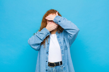 young red head woman covering face with both hands saying no to the camera! refusing pictures or...
