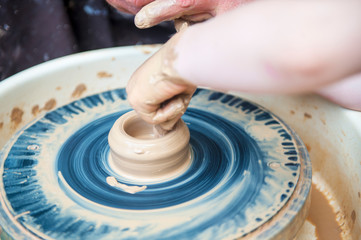The potter makes pottery dishes on potter's wheel.