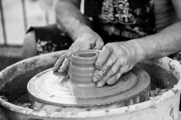 The potter makes pottery dishes on potter's wheel.