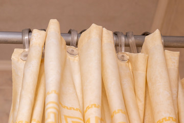 beige shower curtain in the bathroom on the pipe