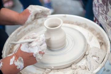 The potter makes pottery dishes on potter's wheel.