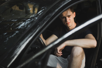 Young man sitting in his car.