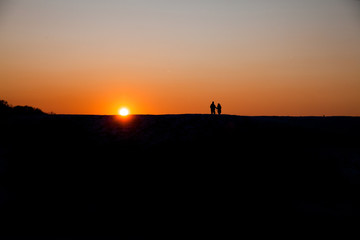Silhouette of two people on the horizon at sunset