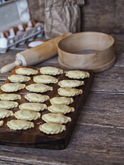 On the kitchen cutting board, ready-made dumplings with ingredients for making dough and various kitchen utensils.