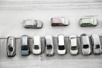 Cars in a row on a parking lot covered by snow, top view. Winter weather, yard of residential district