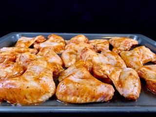 Chicken wings in a marinade on a baking sheet. Cooking chicken with spices in the oven. Fried Chicken Legs and Wings Recipe.