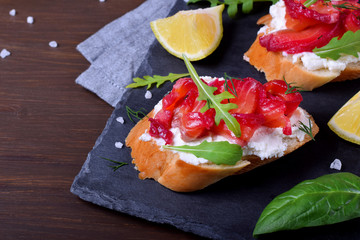 Trout Gravlax on the slices of white bread with ricotta topped with greenery on the stone platter. Nordic cuisine meal
