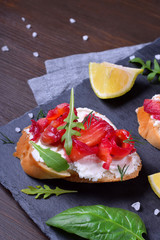 Trout Gravlax on the slices of white bread with ricotta topped with greenery on the stone platter. Nordic cuisine meal