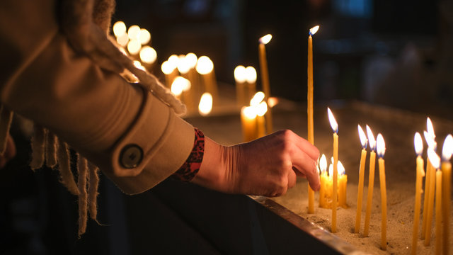 Adult Caucasian light candle in Orthodox Church
