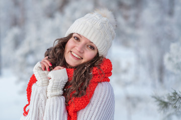 beautiful girl in winter forest in the snow smiling looking at the frame