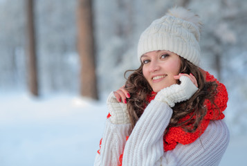 beautiful girl in winter forest in the snow smiling looking at the frame