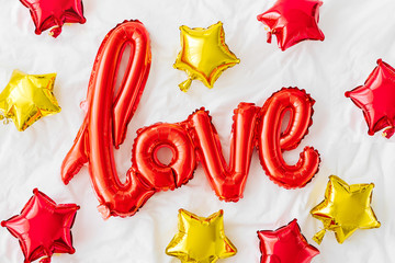 Air Balloons in the shape of the word "Love" on bed. Love concept. Holiday, celebration. Valentine's Day or wedding/bachelorette party decoration. Red Foil balloon