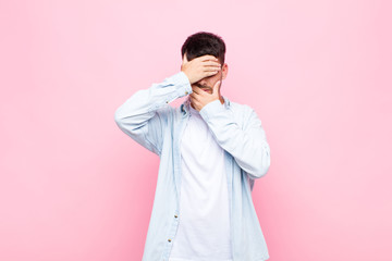 young handsome man covering face with both hands saying no to the camera! refusing pictures or...
