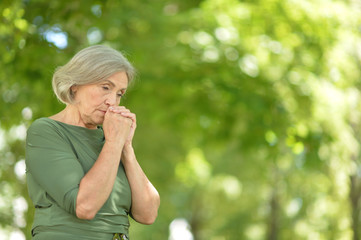 Sad senior beautiful woman in spring park