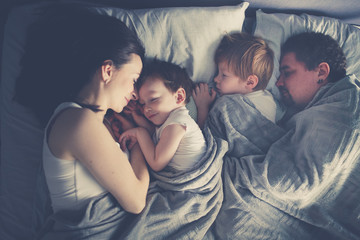 family with two children sleeping in bed,top view