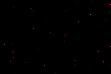 red glowing lights points from fireworks in the night black sky