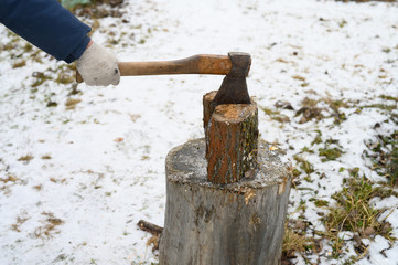 man's hand with an axe chopping wood