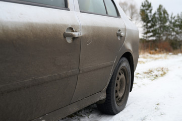 very dirty gray car in the autumn or winter in the mud