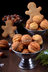 Walnut shaped shortbread cookies with cream filling in a metal cup against the dark background