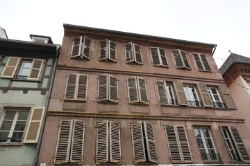 Facade or façade of a historical residential house in Colmar, Alsace, France. The windows have shutters, some of them are closed. the facade is stained by water and time. The house is original  state.