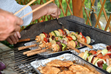 A human puts a spice sauce on meat and vegetables on the grill
