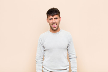 young handsome man feeling disgusted and irritated, sticking tongue out, disliking something nasty...
