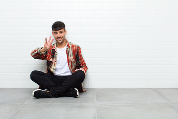 young handsome man smiling and looking friendly, showing number three or third with hand forward,...