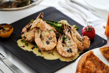 Shrimp in sauce on a black tray, close-up. Catering buffet food in hotel restaurant
