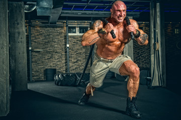 Strong Men pulling big truck tire as part of his training at the Gym