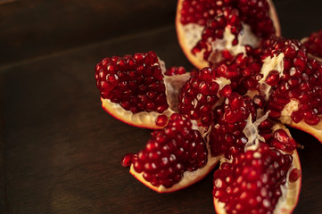 Fresh red pomegranate - cut into pieces on a wooden vintage background, top view