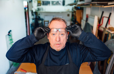 62 year old man putting on safety glasses in the fiber workshop.