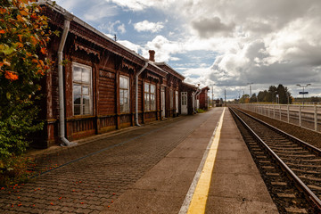 Fototapeta na wymiar Retro train station next to a platform with yellow safety line painted. Showery day.
