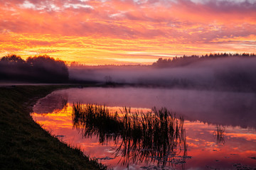 Intensive colors (red, yellow, orange) of sky during sunrise by lake Ozierany. Poland, Europe.