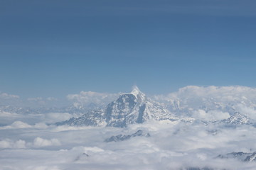 A beautiful photo of a mountain with glacier and snow on it from a height above the clouds