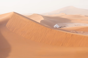 Camp with tent in the desert among sandy dunes. Sunny day in the Sahara during a sand storm in...