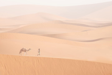 Bedouin and camel on way through sandy desert Nomad leads a camel Caravan in the Sahara during a sand storm in Morocco Desert with camel and nomads Silhouette man Picturesque background nature concept