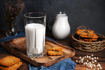 Still life in a rustic style. A glass of milk and a stack of cookies on an old wooden table.