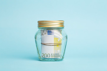 Money euro deposit concept. Euro cash in a glass jar on a blue background. Cash operations, business and banking concept