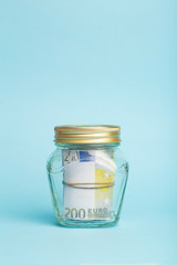 Money euro deposit concept. Euro cash in a glass jar on a blue background. Cash operations, business and banking concept
