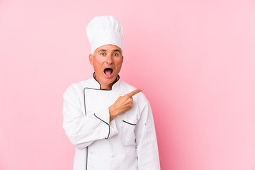 Middle aged cook man isolated pointing to the side