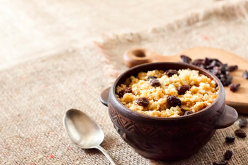 Sweet millet porridge with dark raisins in ceramic rustic bowl