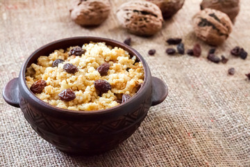 Sweet millet porridge with dark raisins in ceramic rustic bowl