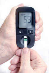 An elderly woman holds a glucometer in her hands and wants to do a blood test for sugar