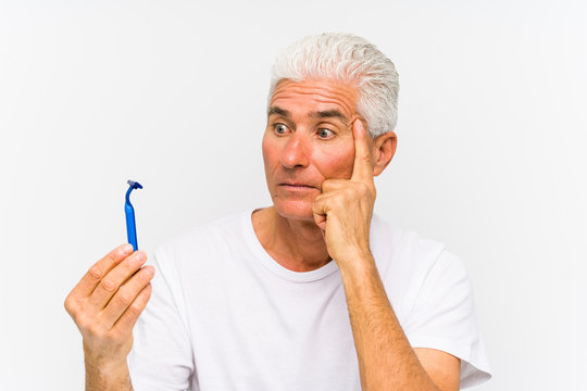 Senior caucasian man holding a razor blade isolated çpointing his temple with finger, thinking, focused on a task. - Powered by Adobe