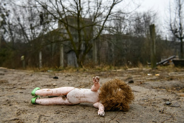 Baby doll lies near fence near entrance to the ghost town of Prypiat in Chornobyl Exclusion Zone,...